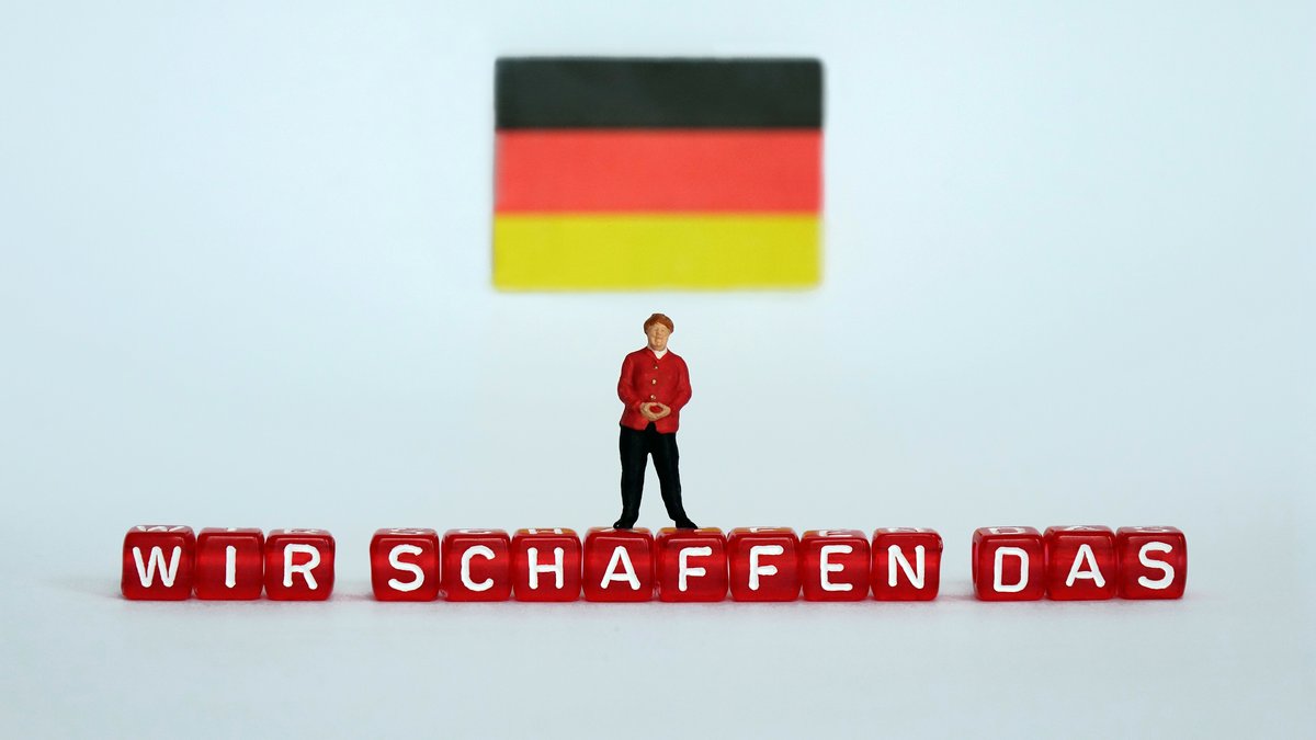 ILLUSTRATION - Eine kleine Figur, die Bundeskanzlerin Angela Merkel darstellen soll, steht unter einer Deutschland-Fahne auf Buchstaben-Würfeln mit dem Schriftzug "WIR SCHAFFEN DAS", aufgenommen am 18.03.2017.