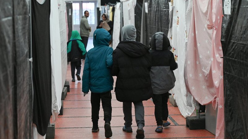 Flüchtlingskinder gehen durch ein Zelt der Flüchtlingsunterkunft