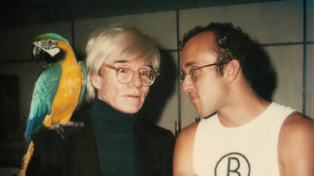 Farbfoto mit Keith Haring und Andy Warhol, dem ein Papagei auf der Schulter sitzt