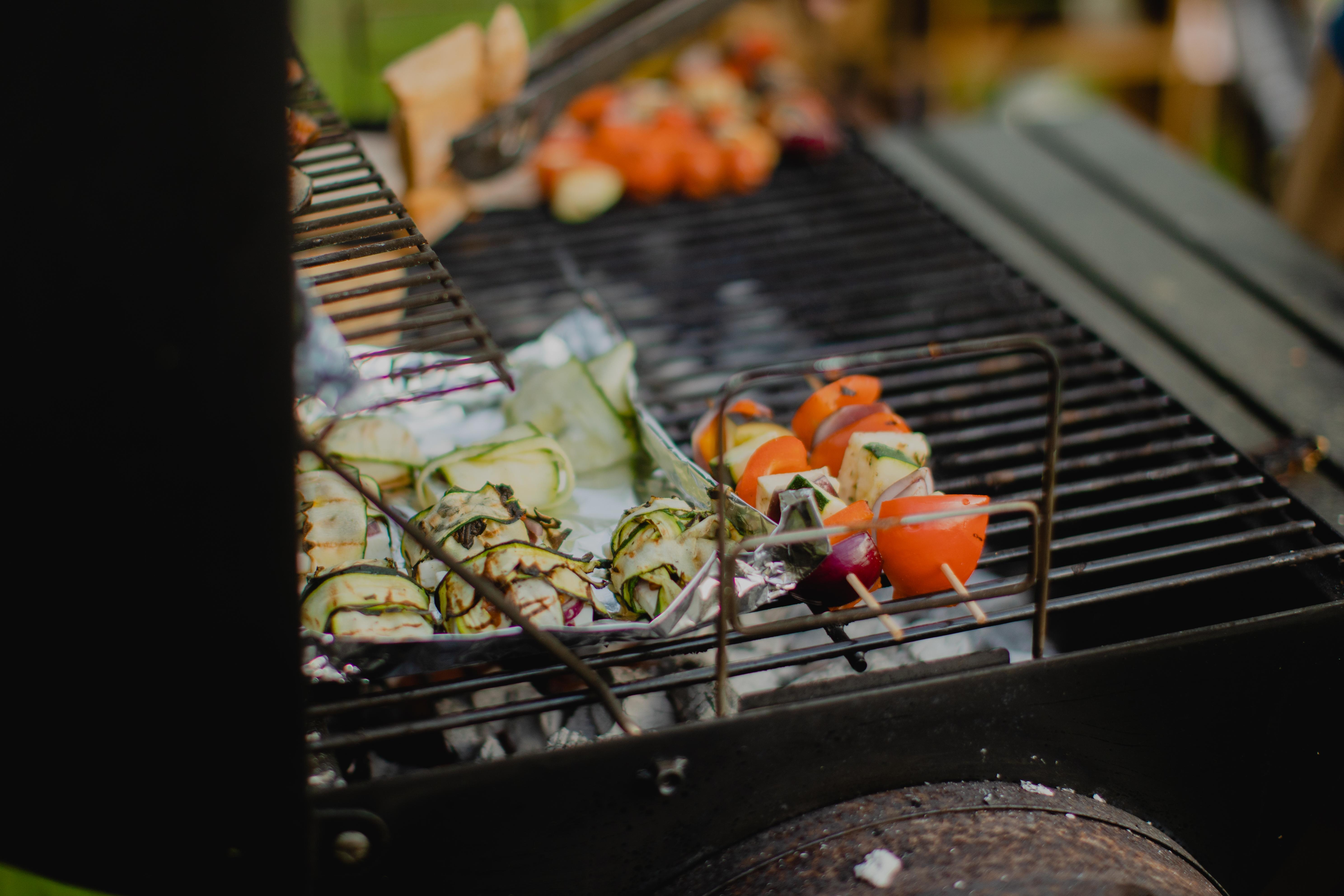 Gemüse und anderes Grillgut liegt auf einem Holzkohlegrill.