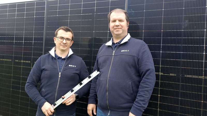 Die Ingenieure Eugen Borgardt (links) und Johann Reis (rechts) mit dem Winkel, mit dem sich Solar-Module an Zäunen aufhängen lassen. | Bild: BR24/Eleonore Birkenstock Die Ingenieure Eugen Borgardt (links) und Johann Reis (rechts) mit dem Winkel, mit dem sich Solar-Module an Zäunen aufhängen lassen.