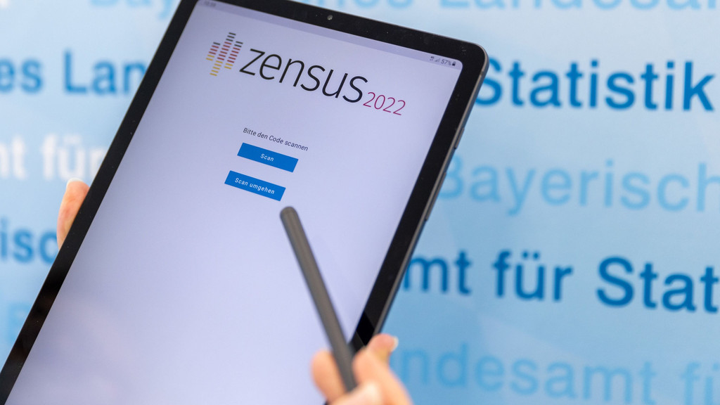 Eine Person hält einen Stift und ein Tablet in der Hand, auf dem das Logo vom Zensus 2022 erkennbar ist. 