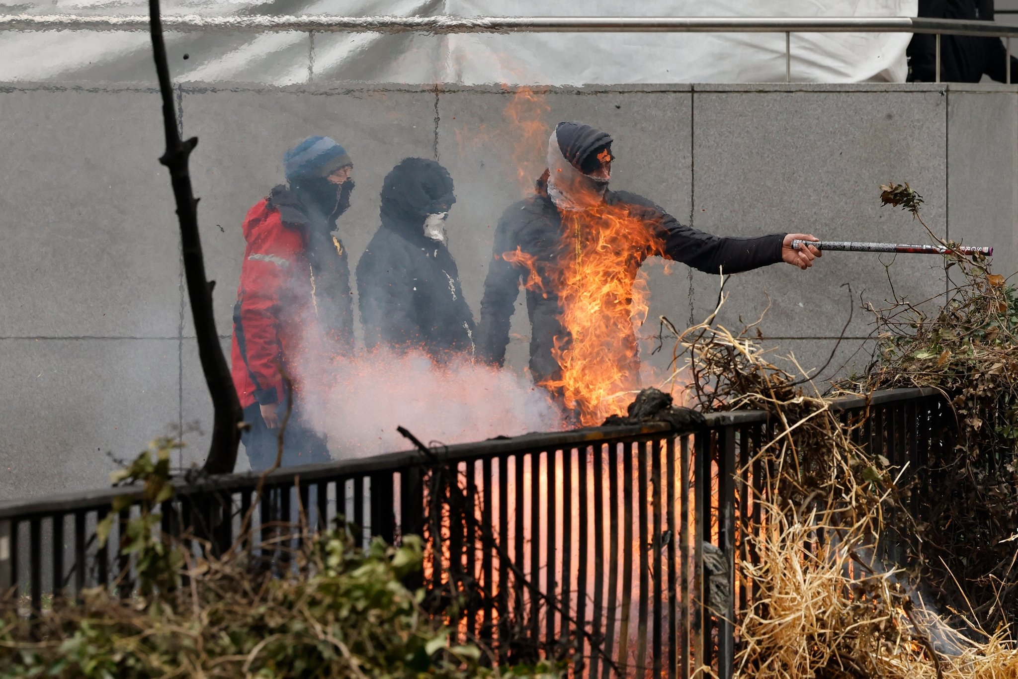 26.03.2024, Belgien, Brüssel: Demonstranten zünden während Bauernprotesten, in der Nähe des Gebäudes des Europäischen Rates, Heu auf einer kleinen Überführung an. Dutzende von Traktoren sperrten die Straßen in der Nähe des Sitzes der Europäischen Union ab, wo die 27 EU-Agrarminister zusammentreffen, um die Krise in diesem Sektor zu erörtern, die zu monatelangen Demonstrationen in der gesamten EU geführt hat. Foto: Geert Vanden Wijngaert/AP/dpa +++ dpa-Bildfunk +++