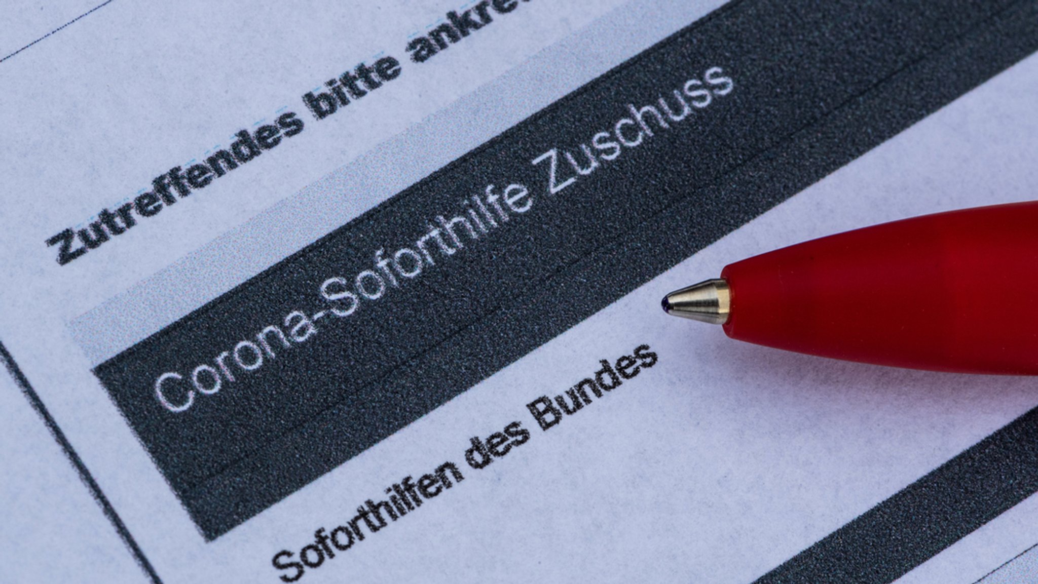 Ein Stift liegt auf einem Antrag für den Corona-Soforthilfe-Zuschuss.