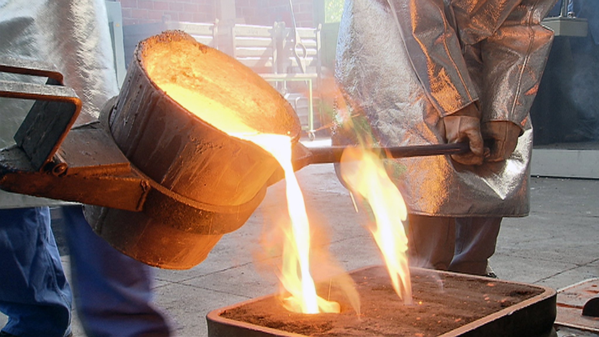 Glühend-heißes Metall wird  aus einem Behälter in eine Form gegossen (Symbolbild).