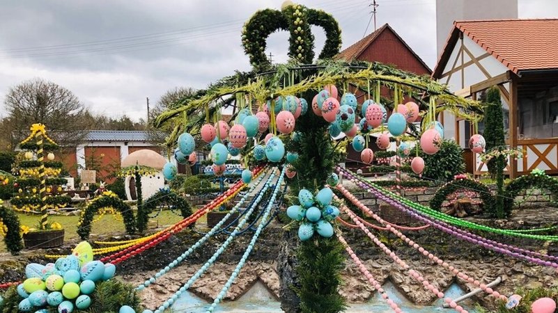 Ein mit bunten Eiern und Ranken geschmückter Osterbrunnen. 