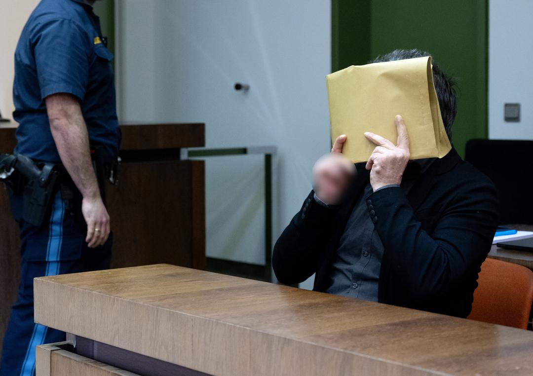 Der wegen des Besitzes und der gewerbsmäßigen Verbreitung kinder- und jugendpornografischer Schriften Angeklagte sitzt vor Prozessbeginn am Landgericht im Gerichtssaal und verdeckt sein Gesicht. 