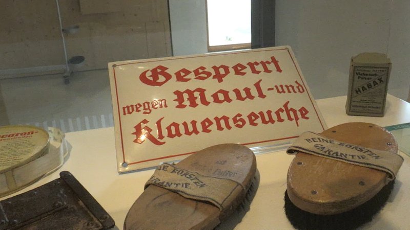Schild mit der Aufschrift: "Gesperrt wegen Maul- und Klauenseuche", davor alte Bürsten
