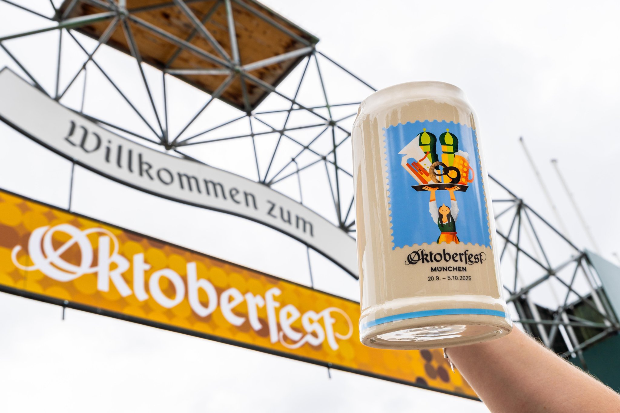 Der offizielle Oktoberfest 2025 Sammlerkrug wir von einem Mann vor den Schrifzug: Willkommen zum Oktoberfest, auf der Theresienwiese in München gehalten.  | Bild: picture alliance/CHROMORANGE/Michael Bihlmayer Der offizielle Oktoberfest 2025 Sammlerkrug wir von einem Mann vor den Schrifzug: Willkommen zum Oktoberfest, auf der Theresienwiese in München gehalten.