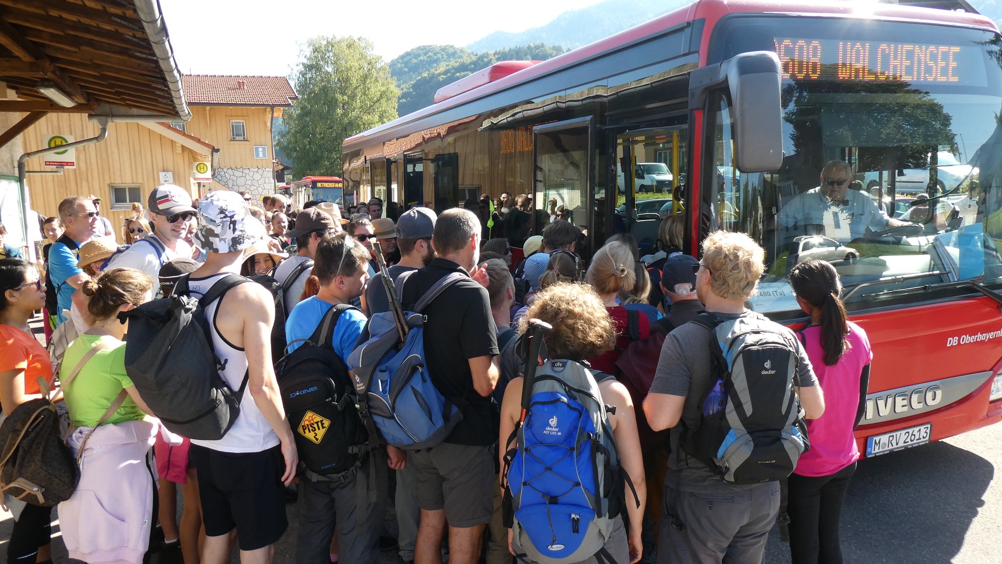 Eine Menschentraube steht an einem Bus an, der die Aufschrift "Walchensee" trägt.