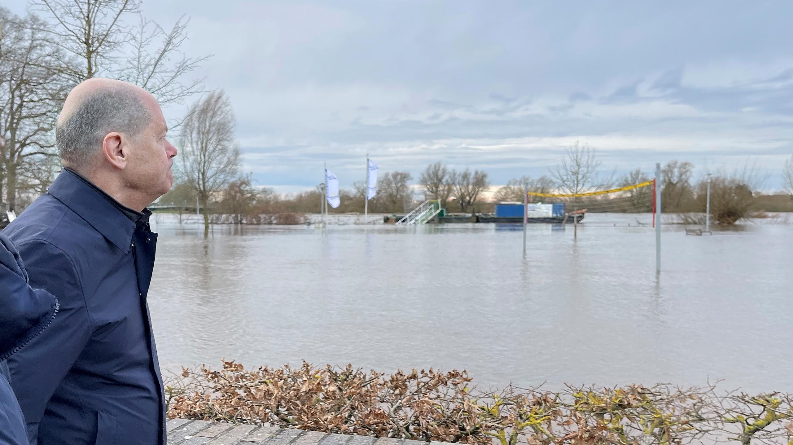 Bundeskanzler Olaf Scholz (SPD) geht an einem überfluteten gelände entlang. Scholz hat sich per Rundflug mit einem Helikopter der Luftwaffe einen Eindruck über die Hochwasserlage im Norden Niedersachsens verschafft.