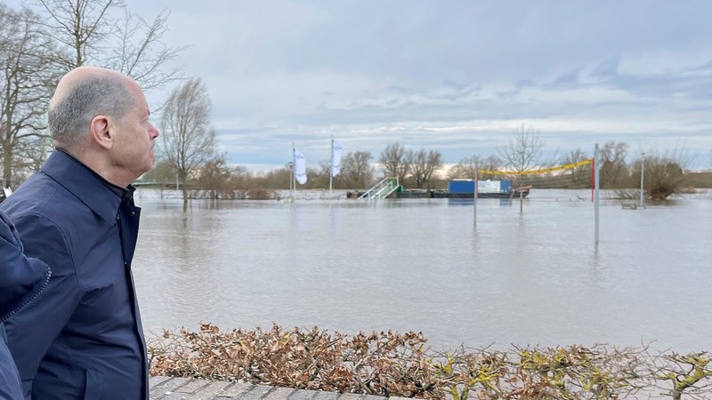 Bundeskanzler Olaf Scholz (SPD) geht an einem überfluteten gelände entlang. Scholz hat sich per Rundflug mit einem Helikopter der Luftwaffe einen Eindruck über die Hochwasserlage im Norden Niedersachsens verschafft.