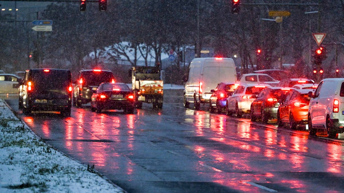 Autos auf einer nassen Straße, am Rand ist Schnee zu sehen.