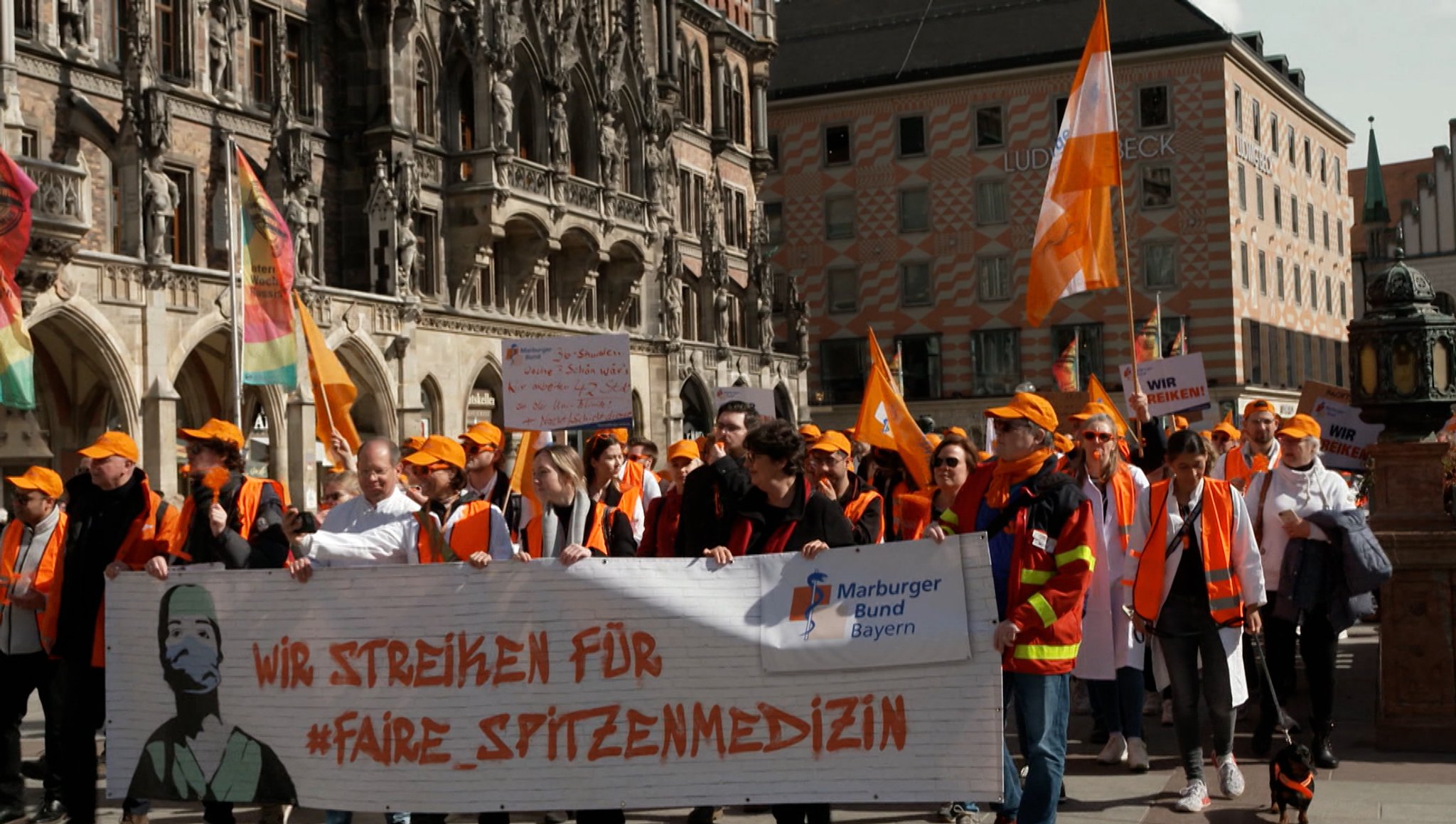 Ärztedemo auf dem Münchner Marienplatz. Ganz vorne ein großes Transparent: Wir streiken für faire Spitzenmedizin.