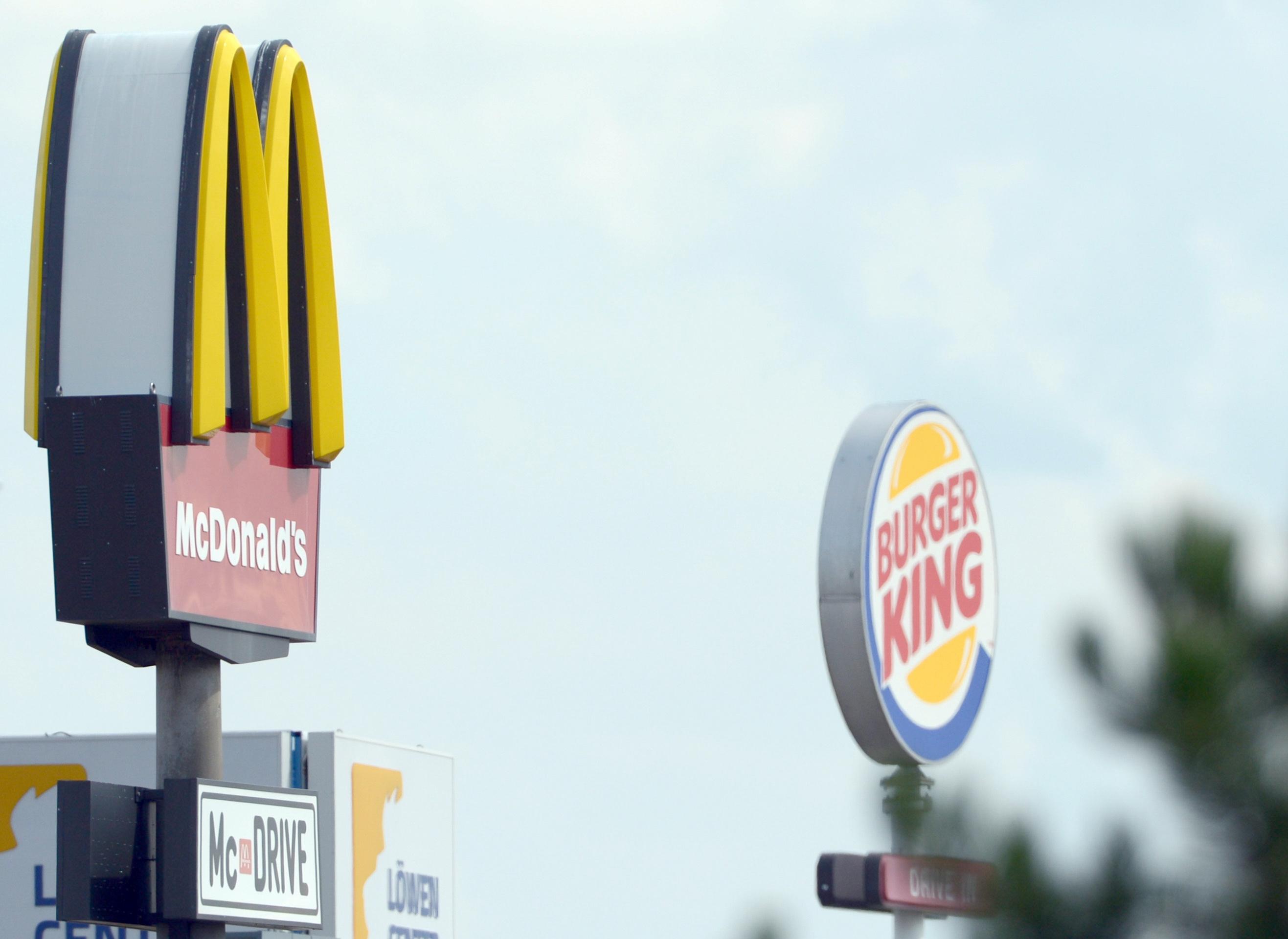 Die Logos der Fastfoodketten McDonalds (l.) und Burger King stehen sich in Leipzig (Sachsen) gegenüber.