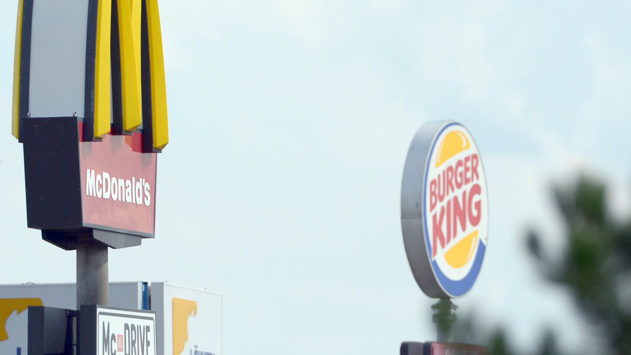 Die Logos der Fastfoodketten McDonalds (l.) und Burger King stehen sich in Leipzig (Sachsen) gegenüber.