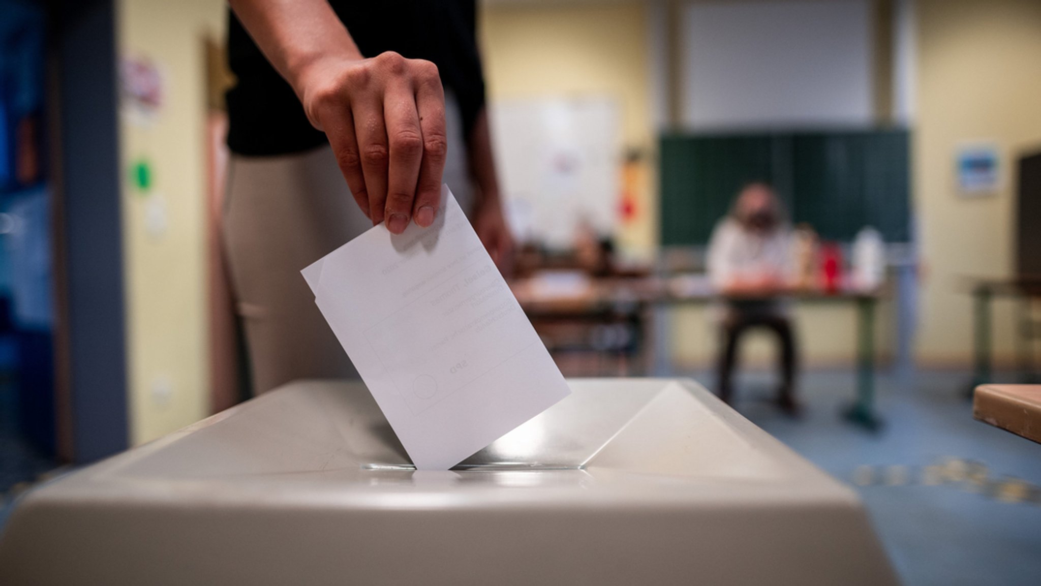 Eine Frau wirft einen Wahlschein in eine Wahlurne. 