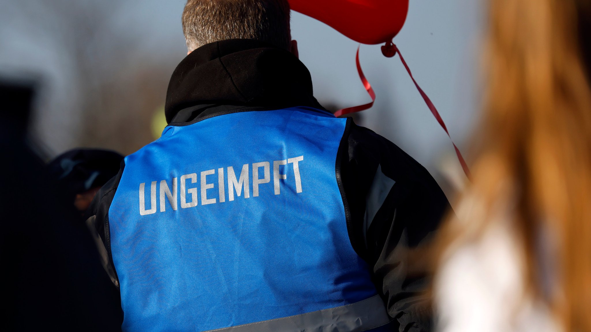 Ein Teilnehmer einer Demo im März 2022 in Düsseldorf trägt eine blaue Weste mit der Aufschrift "ungeimpft".