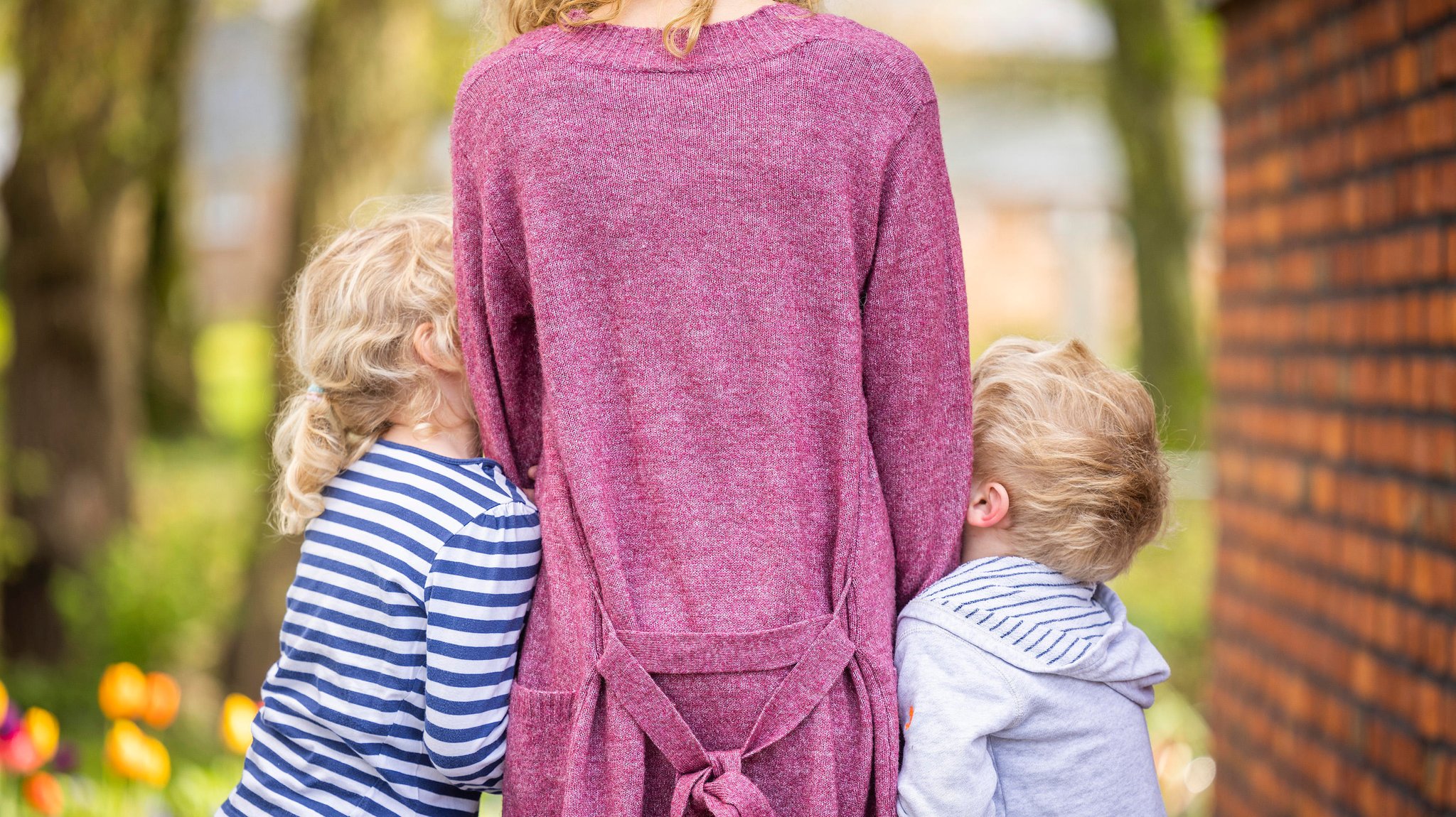 Eine Frau steht mit zwei Kindern in einem Garten (Symbolbild)