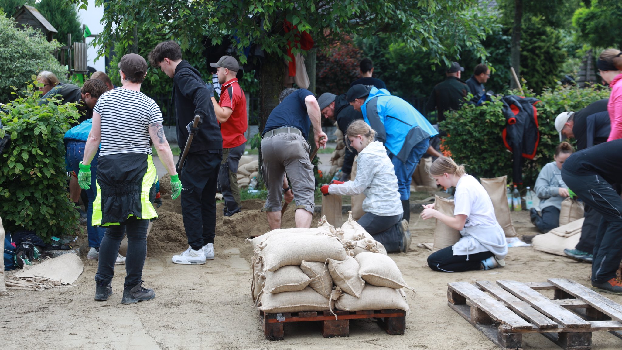 Eine Gruppe Menschen befüllt Sandsäcke für den Hochwasserschutz