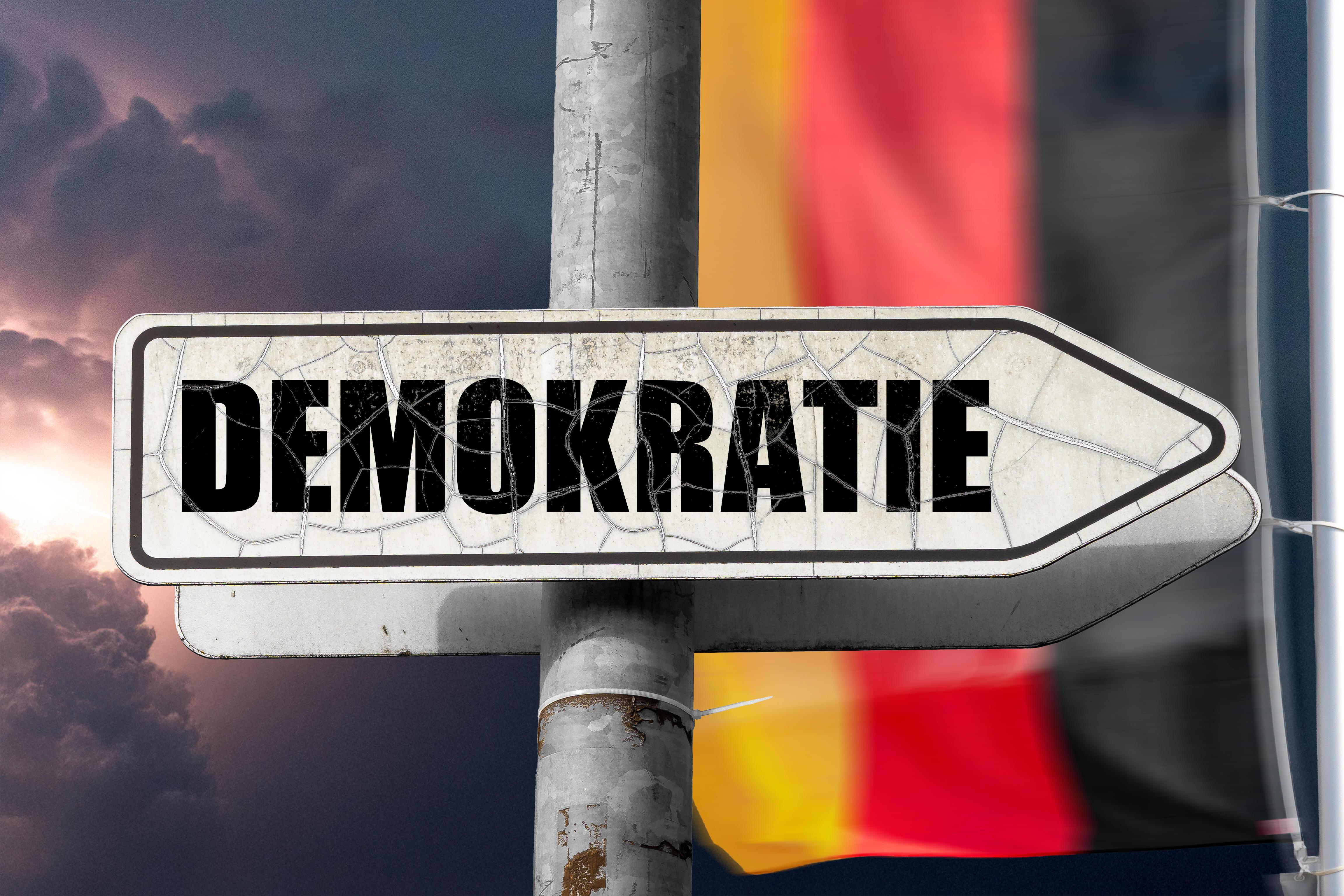 (Symbolbild) Ein Pfeilschild mit der Aufschrift "Demokratie".