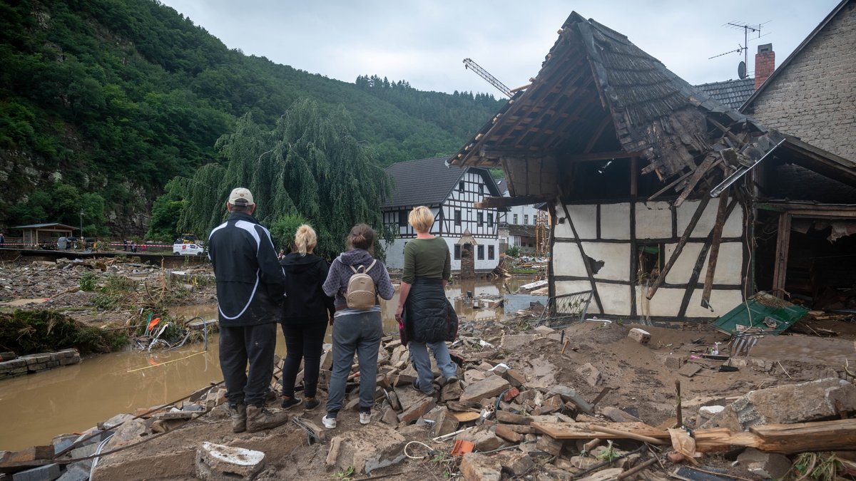 Menschen schauen in dem Ort im Kreis Ahrweiler nach dem Unwetter auf die Zerstörungen.