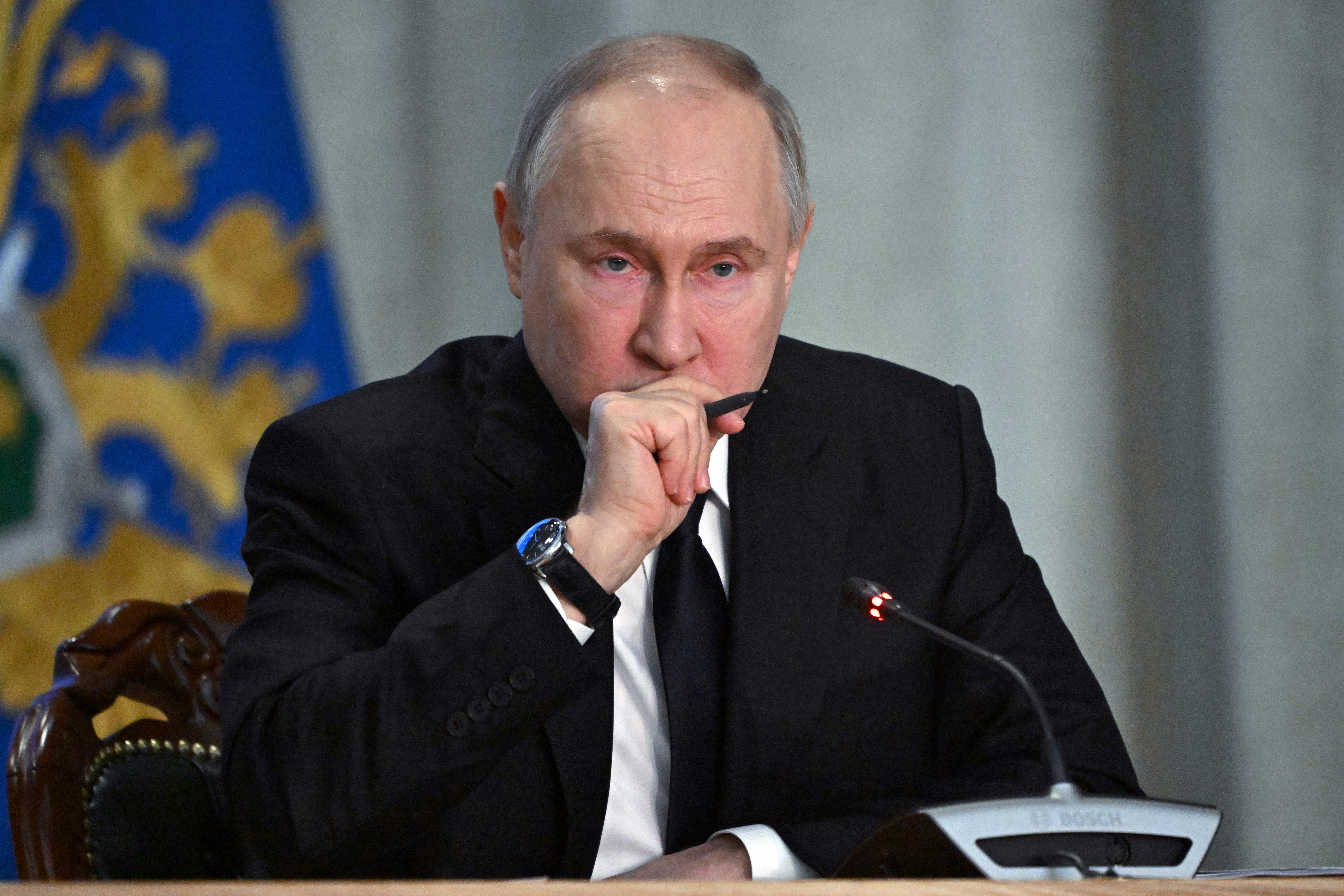 Der russische Präsident vor einem Mikrofon, einen Stift in der Hand haltend