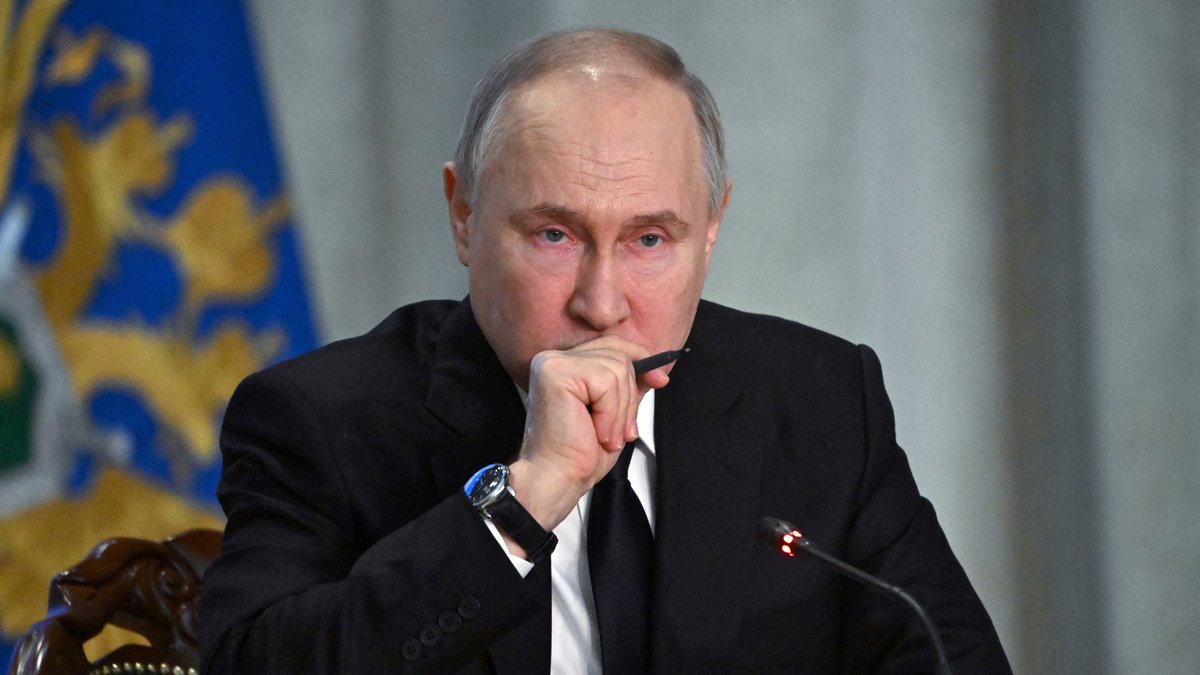 Der russische Präsident vor einem Mikrofon, einen Stift in der Hand haltend