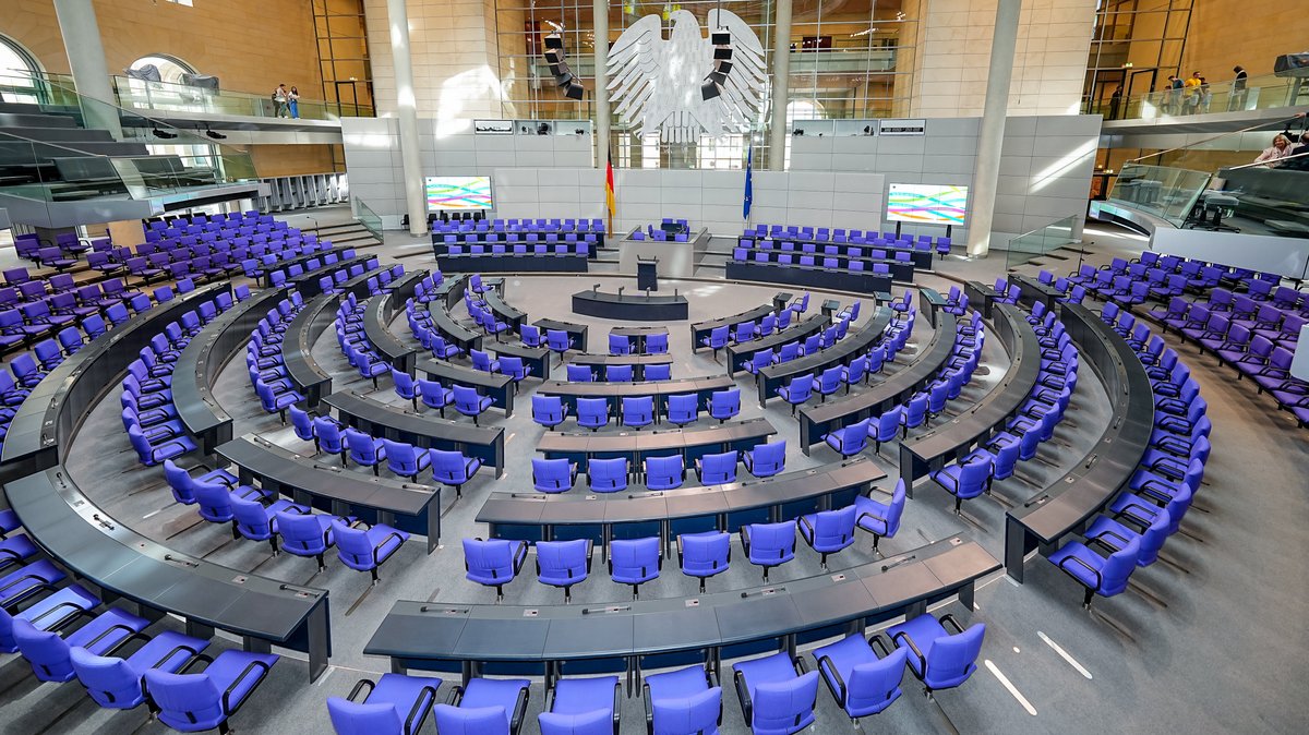 Berlin: Der Plenarsaal des Deutschen Bundestages mit den blauvioletten, jedoch leeren Stühlen, in der Mitte des Reichstagsgebäudes (Archivbild)