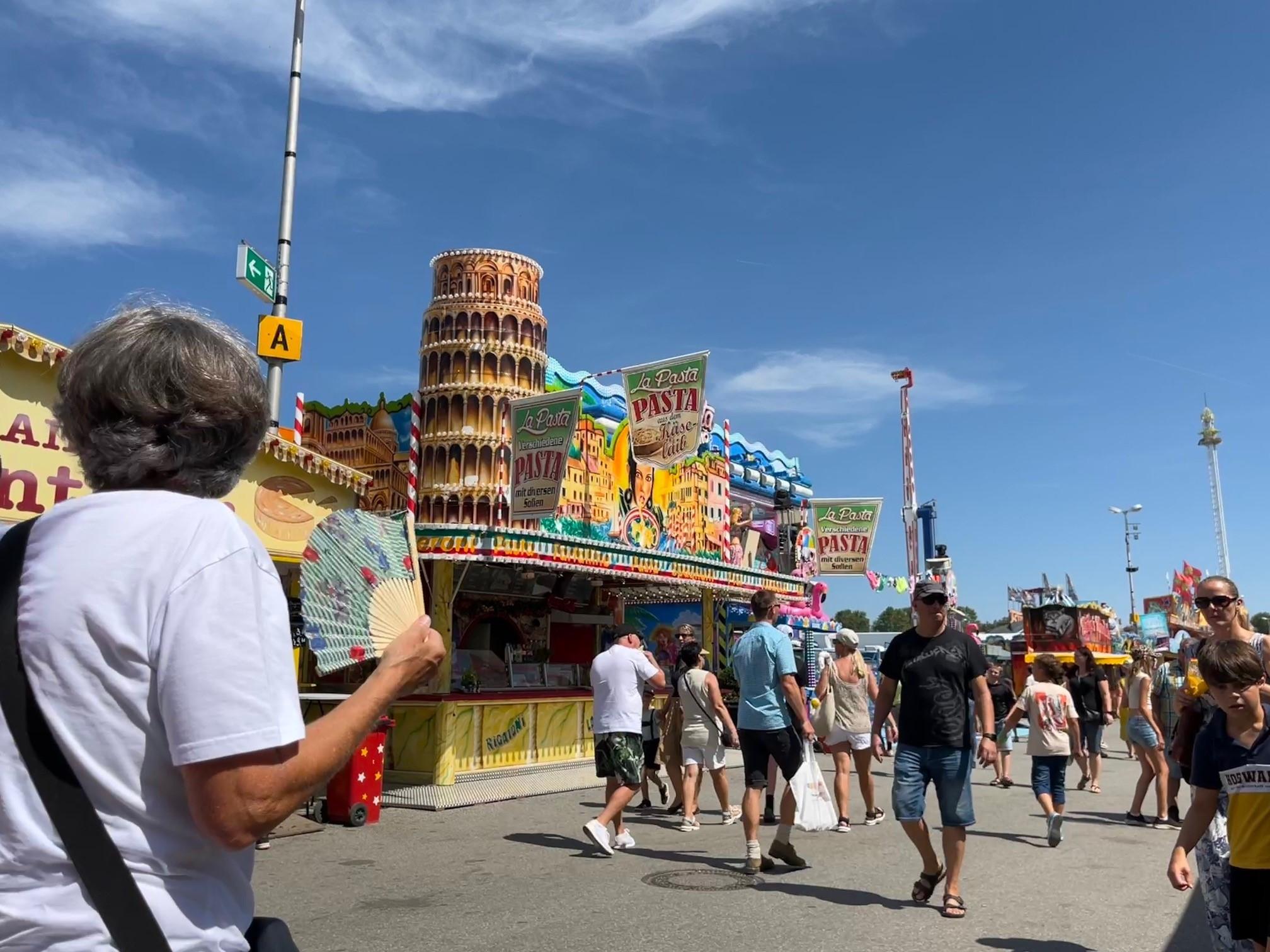 Eine Besucherin auf dem Gäubodenvolksfest mit Fächer. Wegen der Hitze sind die Bierzelte bislang nur mäßig besucht.