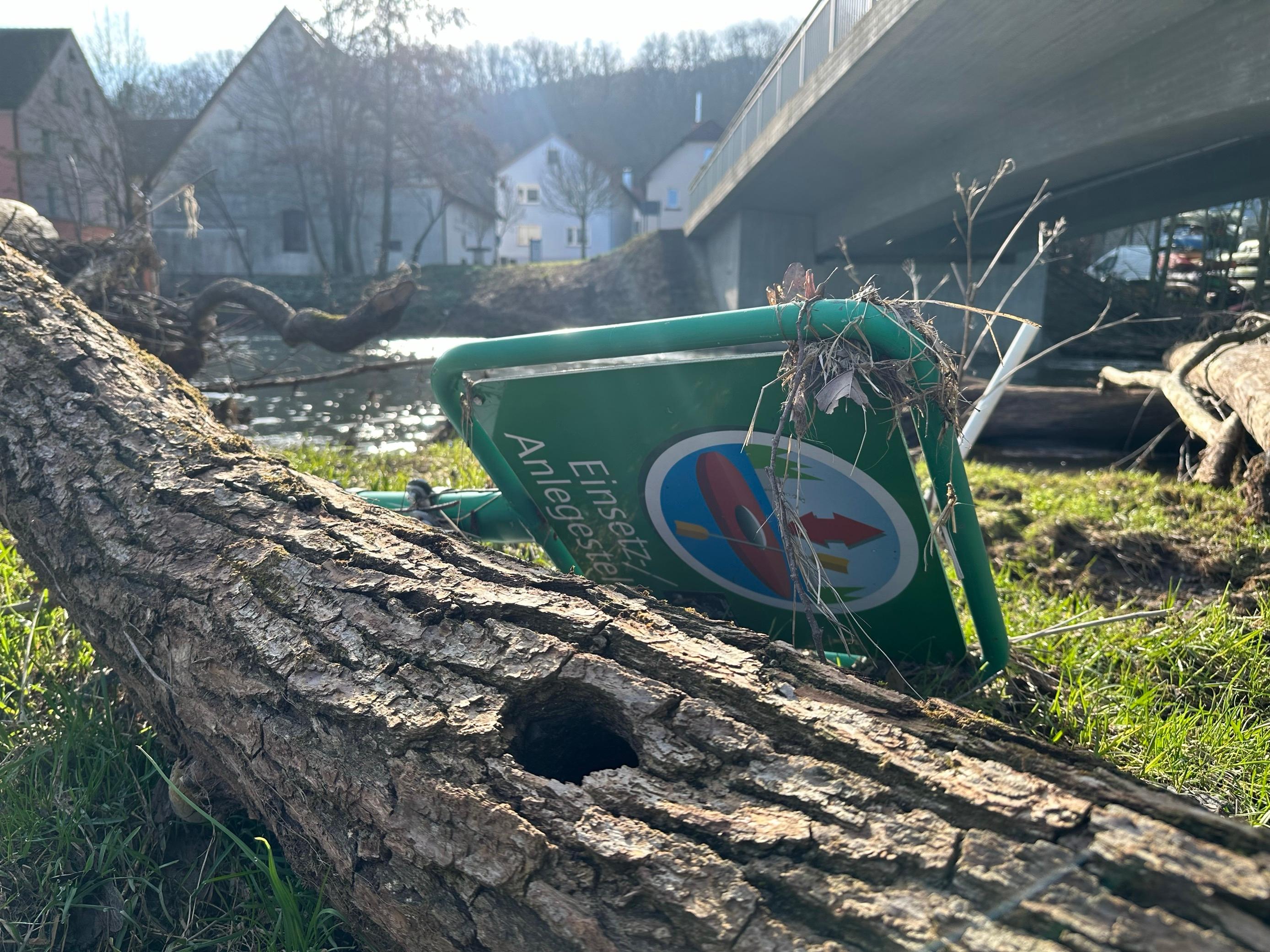 Liegende Bäume und ein liegendes "Paddelschild" an der Fränkischen Saale im Landkreis Bad Kissingen