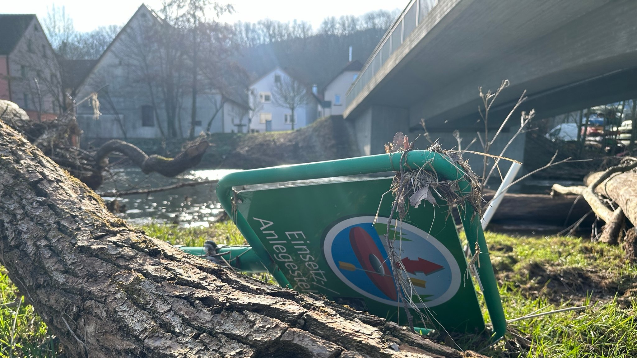 Liegende Bäume und ein liegendes "Paddelschild" an der Fränkischen Saale im Landkreis Bad Kissingen