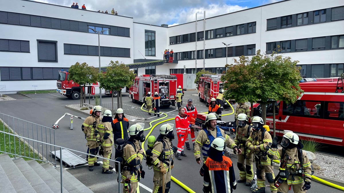 Einsatzkräfte von Feuerwehr und Rettungsdienst stehen in einem Innenhof.