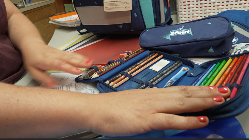 Eine Mitarbeiterin des "Buntstift" zeigt ein gefülltes Mäppchen her. | Bild: BR/Laura Wagmann Eine Mitarbeiterin des "Buntstift" zeigt ein gefülltes Mäppchen her.