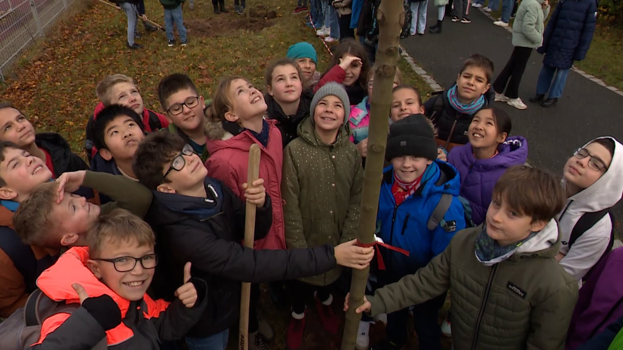 Fünftklässler lachen bei der Baumpflanzaktion in die Kamera.