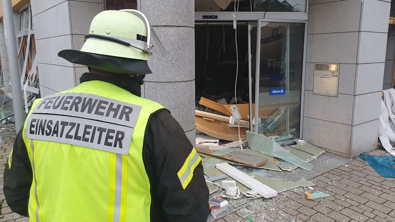 Feuerwehrmann steht vor Bankfiliale, in der ein Geldautomat gesprengt wurde.