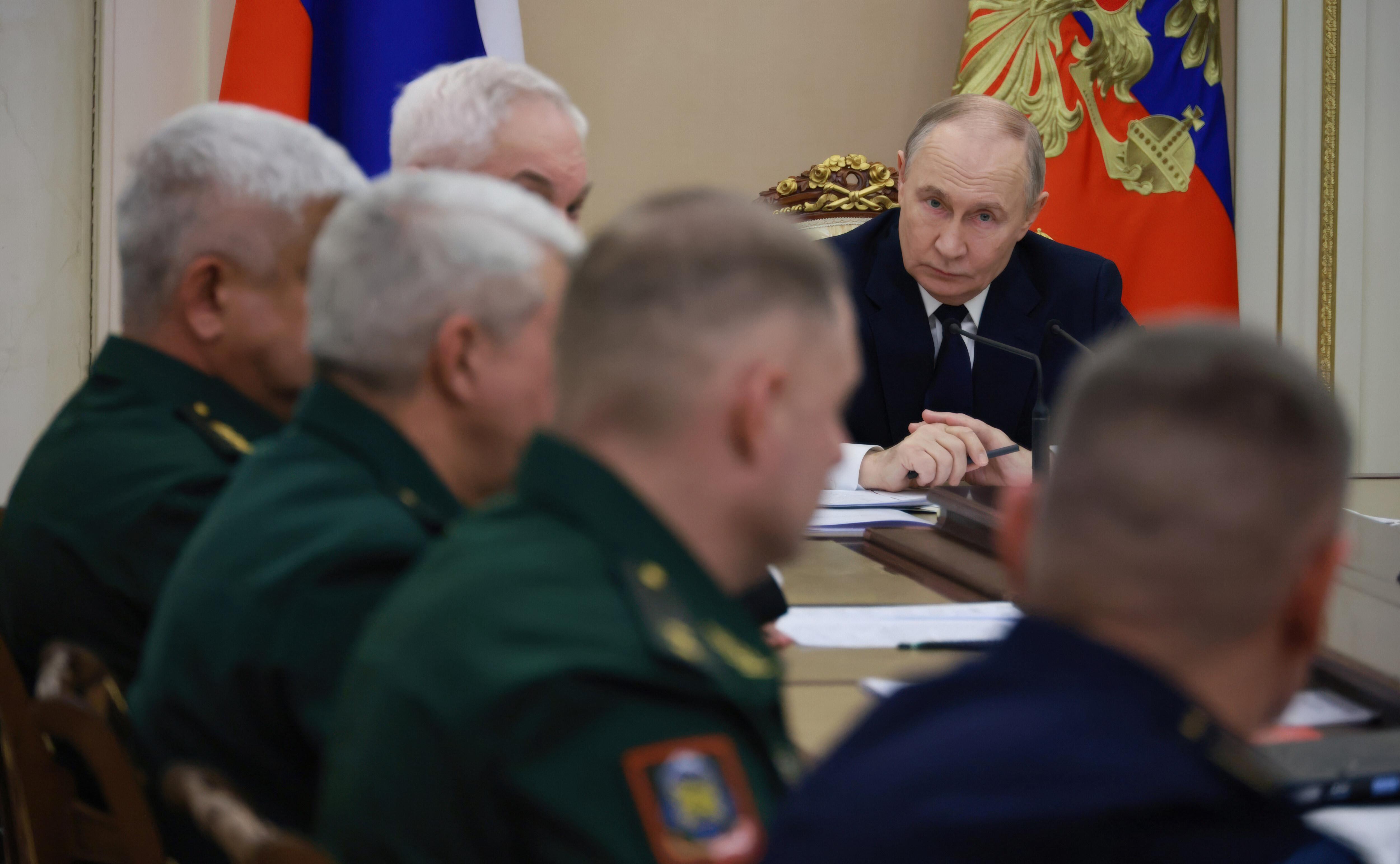 Der russische Präsident an einem Sitzungstisch mit Uniformierten