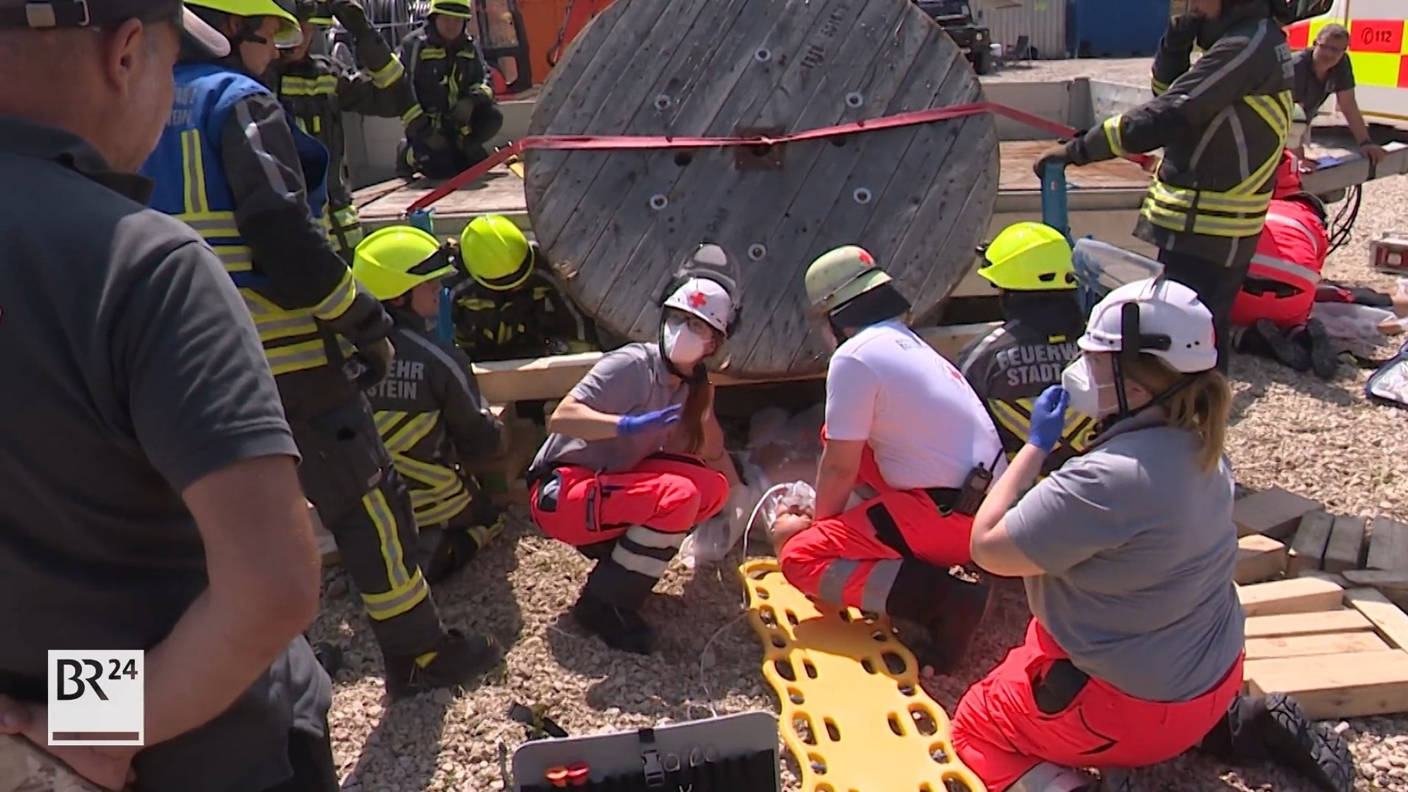 Notfallsanitäter und Feuerwehrleute befreien eine Puppe, die unter einer Kabeltrommel eingeklemmt wurde.