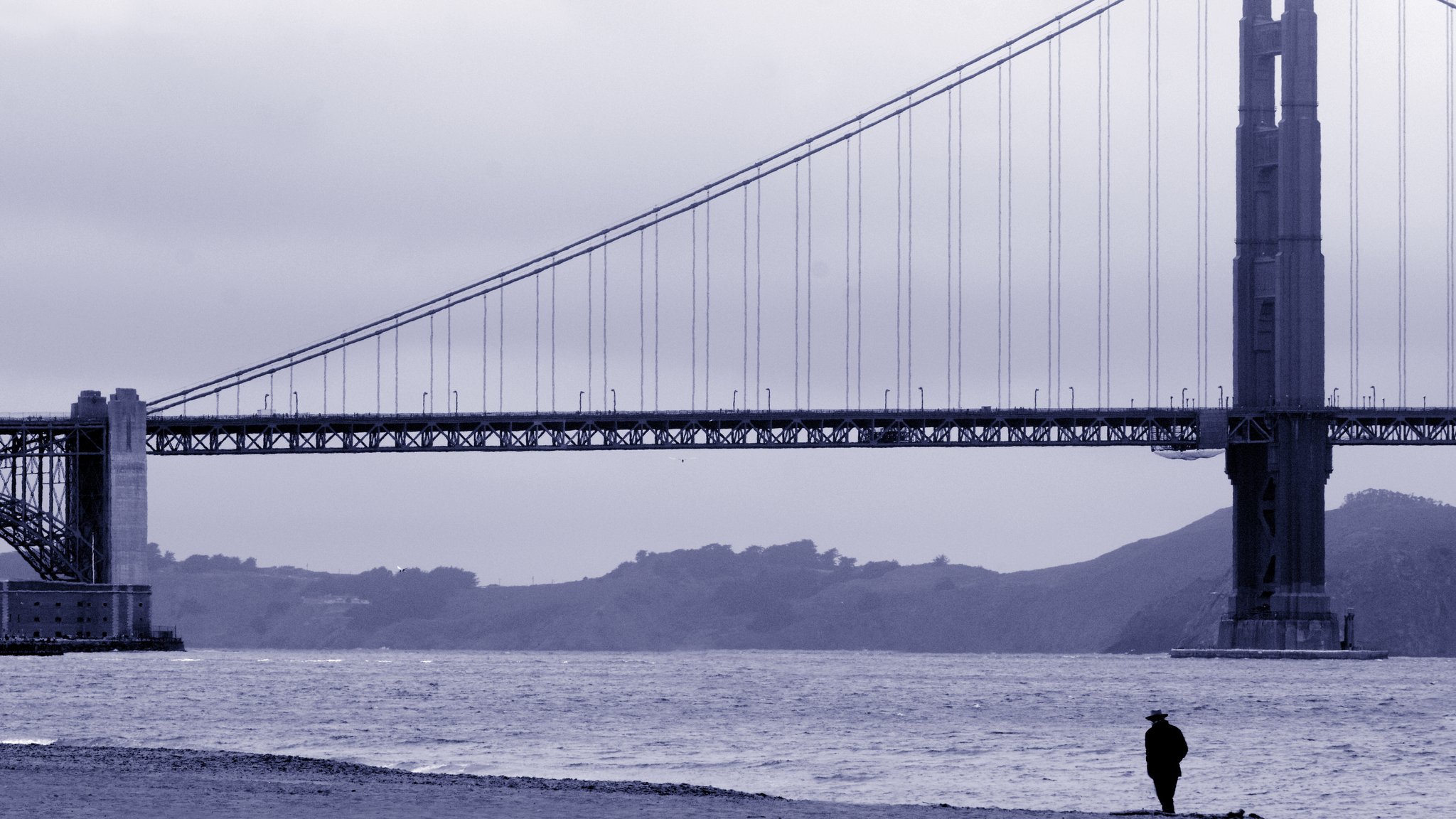 Mann geht am Ufer vor der Golden Gate Bridge spazieren 