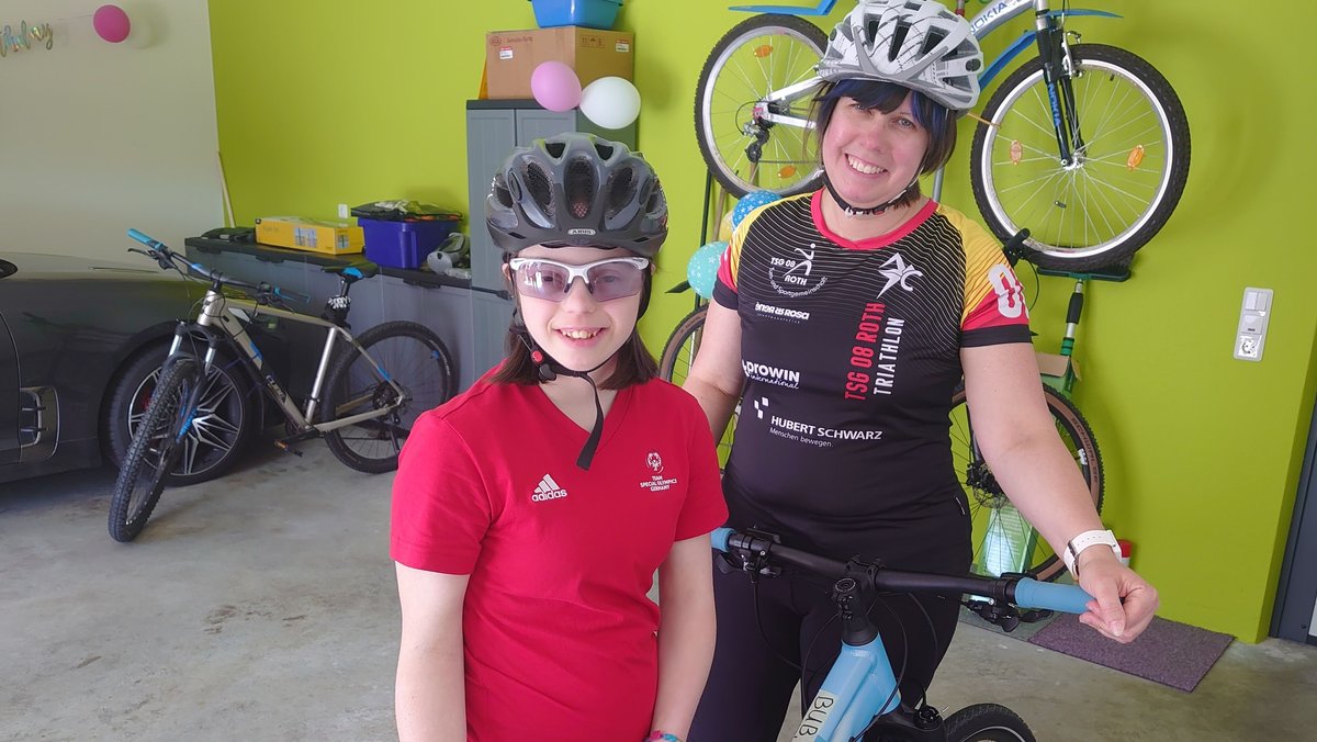 Tatjana Bub steht mit ihrer Mutter und Trainerin Monika Hackner-Bub zusammen in der Garage mit den Fahrrädern.