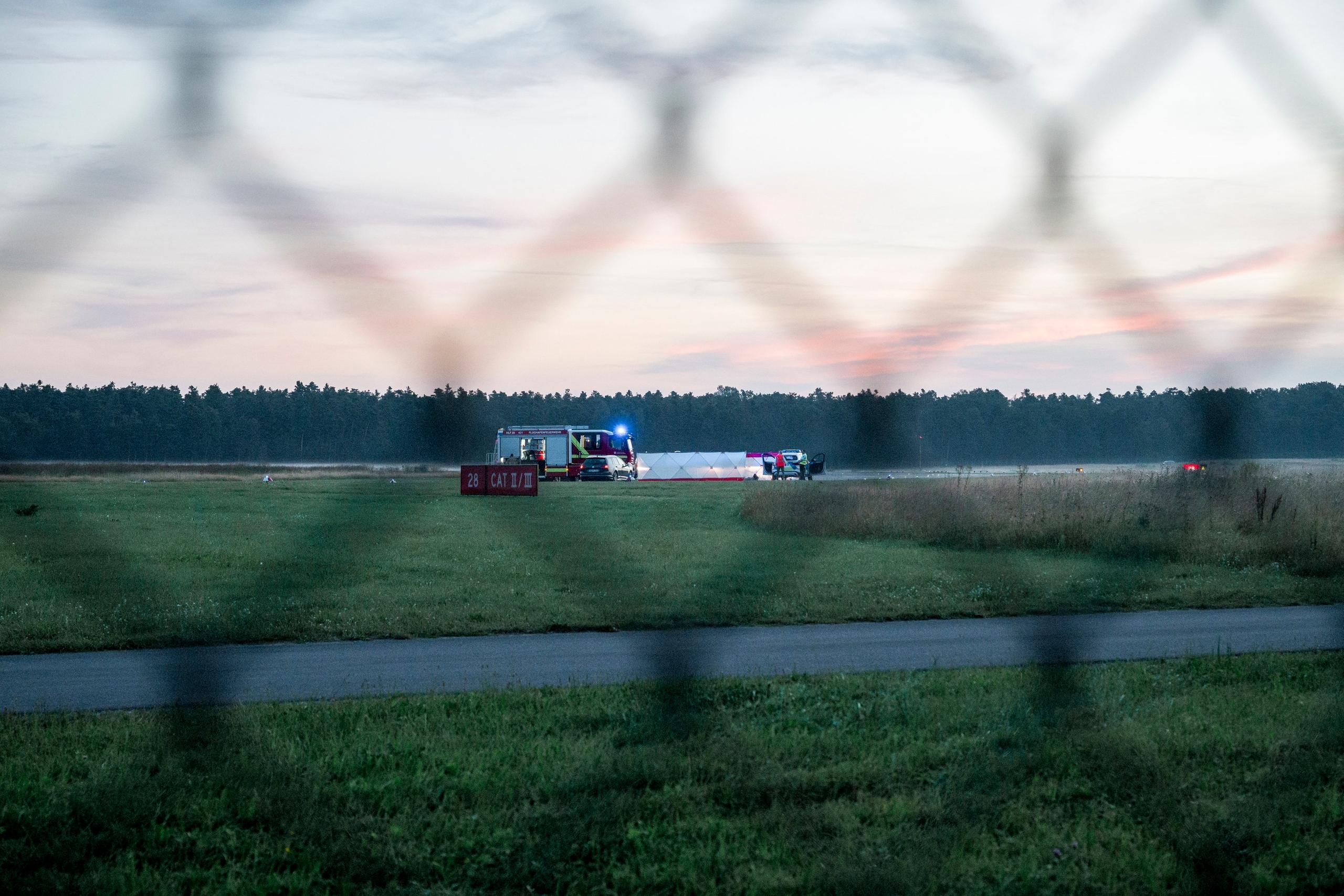 15.08.2024, Bayern, Nürnberg: Polizisten arbeiten hinter Sichtschutzblenden an Aktivisten der Klima-Initiative Letzte Generation auf dem Nürnberger Flughafen. Zwei Aktivisten hatten sich mittels zweier Bolzenschneider Zugang verschafft und klebten sich auf das Rollfeld. Foto: Daniel Vogl/dpa +++ dpa-Bildfunk +++