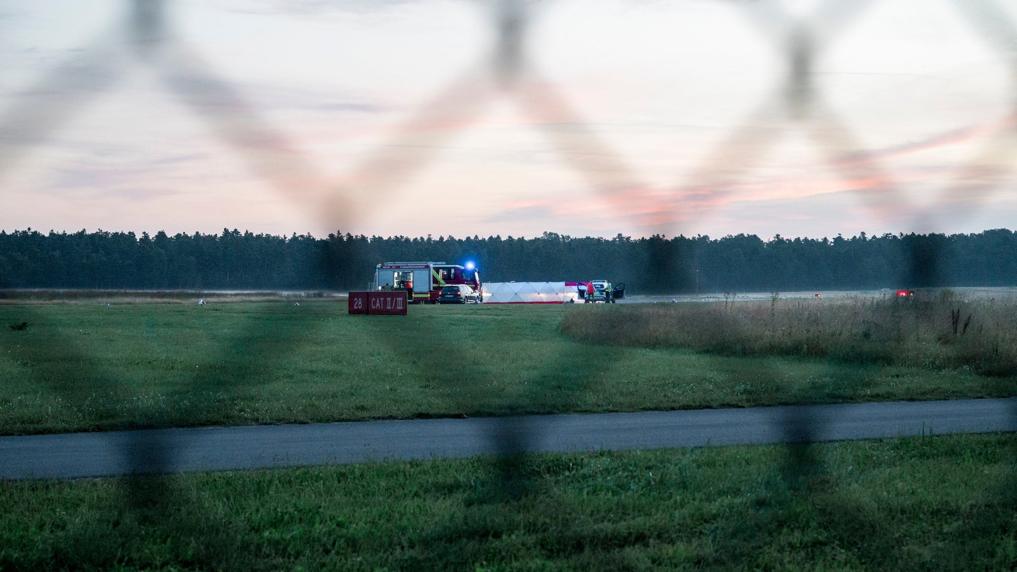 15.08.2024, Bayern, Nürnberg: Polizisten arbeiten hinter Sichtschutzblenden an Aktivisten der Klima-Initiative Letzte Generation auf dem Nürnberger Flughafen. Zwei Aktivisten hatten sich mittels zweier Bolzenschneider Zugang verschafft und klebten sich auf das Rollfeld. Foto: Daniel Vogl/dpa +++ dpa-Bildfunk +++