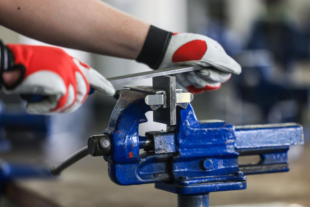 Ein Auszubildender zum Mechatroniker bearbeitet in einer Ausbildungswerkstatt an einem Schraubstock ein Werkstück.  (Symbolbild)