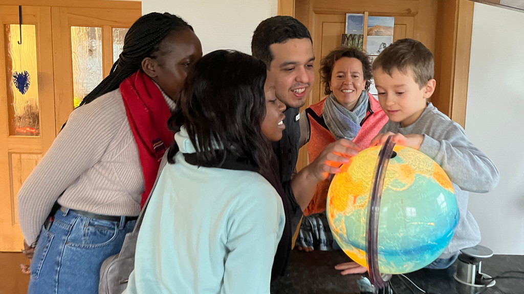 Fünf Personen schauen gemeinsam auf einen Globus - darunter Schüler Matthias, seine Mutter Andrea und die beiden Kenianerinnen Flacita und Peris.