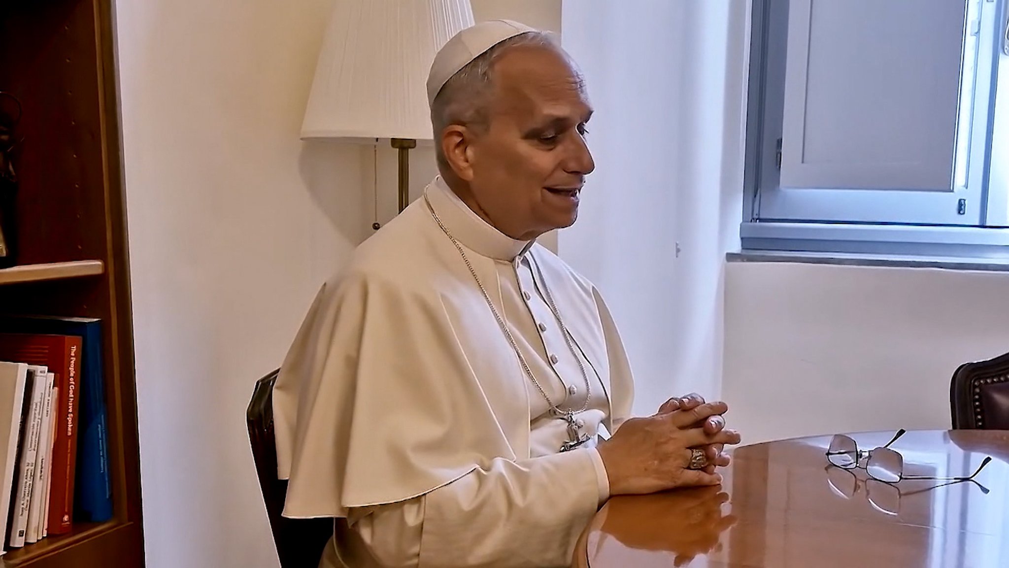 Papst Leo XIV. sitzt mit gefalteten Händen auf einem Stuhl.