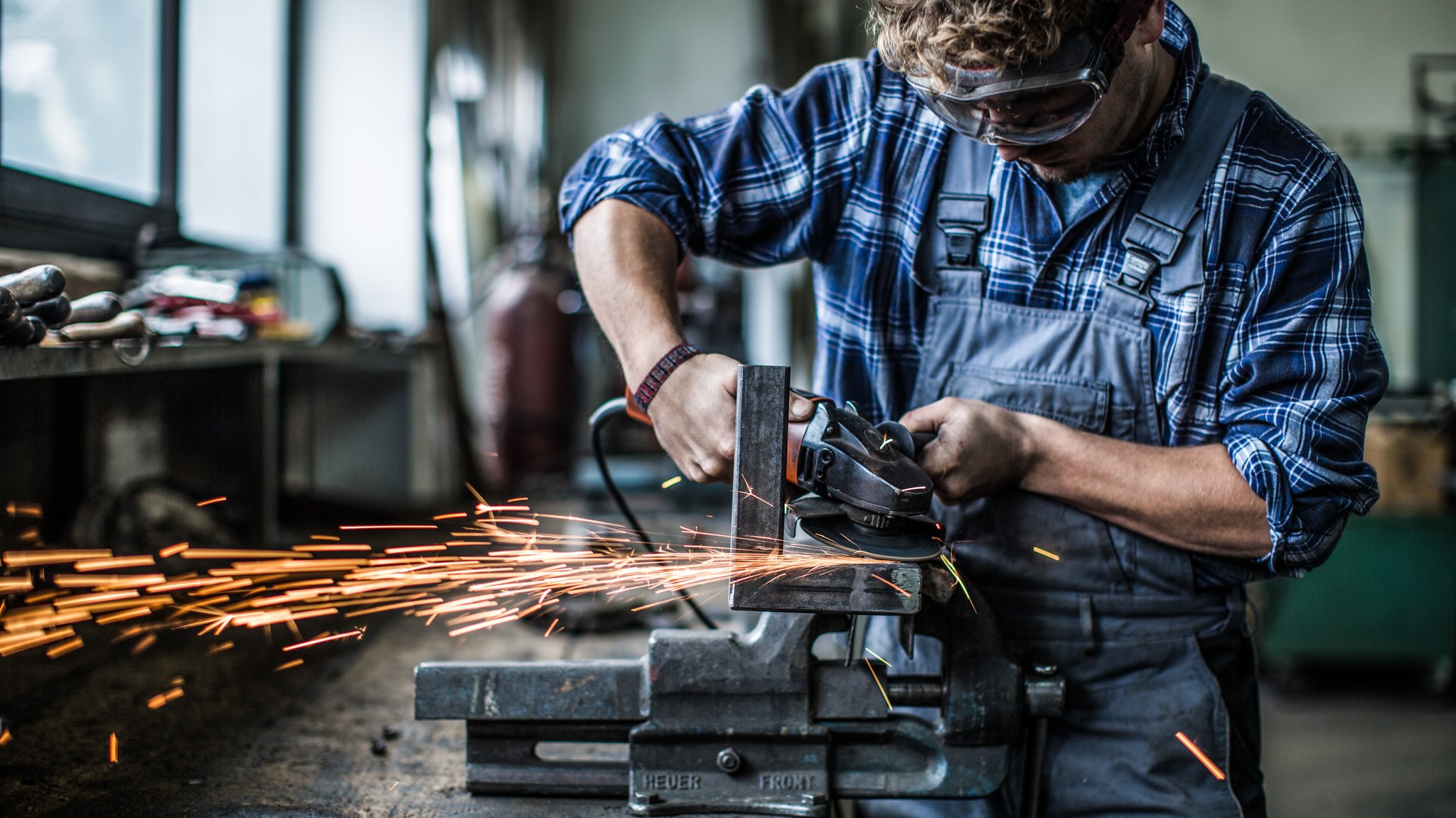 Handwerker beim Einglätten und Überflexen einer Schweißnaht.