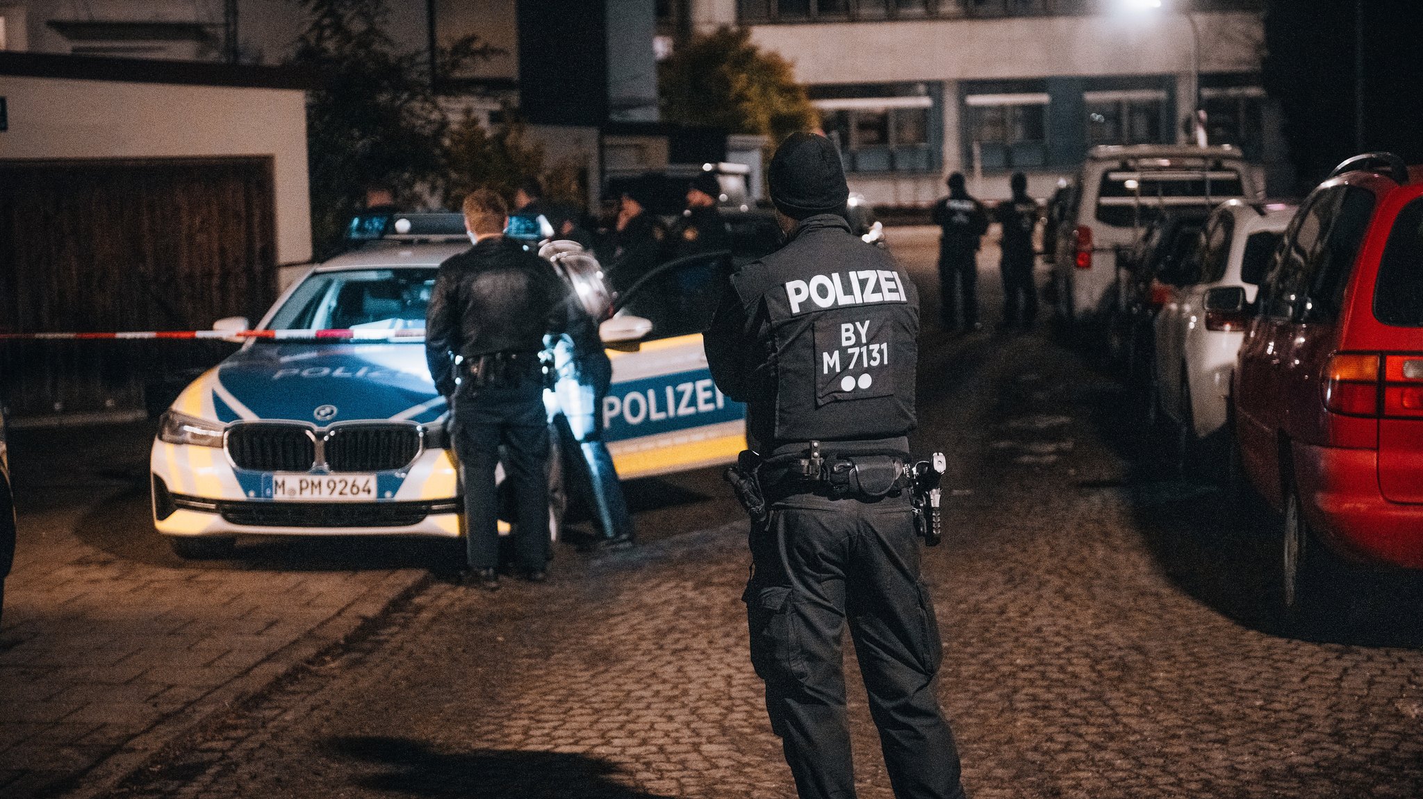 Mehrere Einsatzkräfte der Polizei stehen vor einem Gebäude. Dort ist auch ein Absperrband zu sehen. Am rechten Bildrand sind mehrere Autos. | Bild: NEWS5 / Sebastian Pieknik Mehrere Einsatzkräfte der Polizei stehen vor einem Gebäude. Dort ist auch ein Absperrband zu sehen. Am rechten Bildrand sind mehrere Autos.