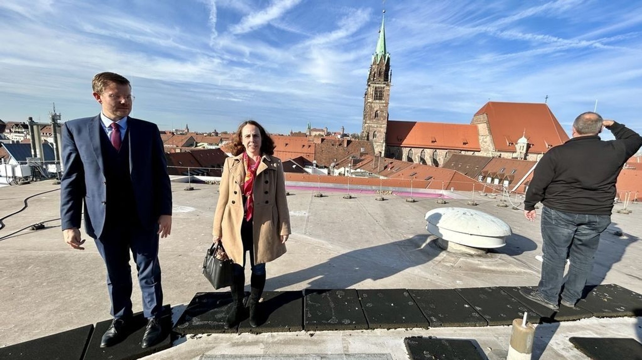 Menschen stehen auf dem Dach eines Gebäudes in Nürnberg, im Hintergrund die Lorenzkirche.