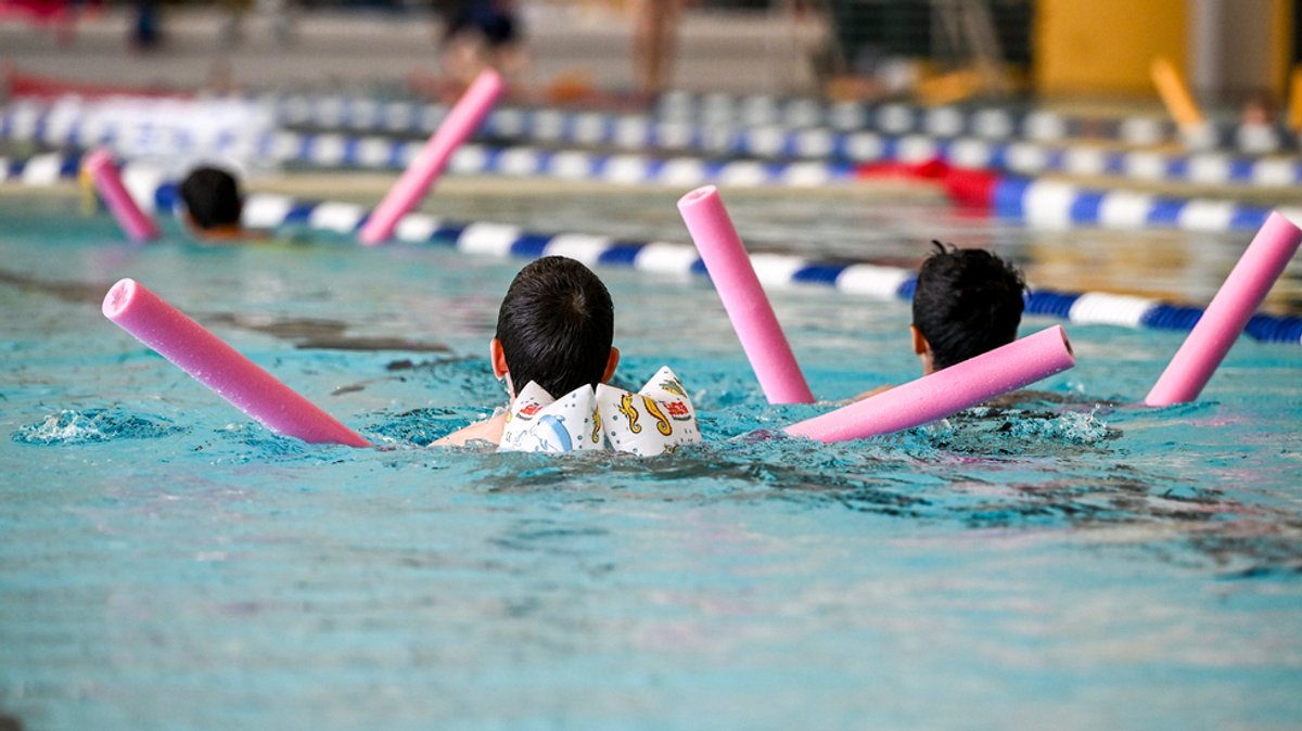 Kinder mit Schwimmhilfen im Wasser.