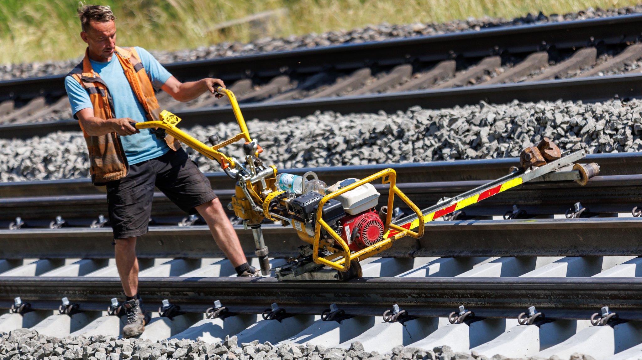 Ein Arbeiter fixiert im Sommer 2023 auf einer Baustelle der Bahnstrecke Würzburg - Nürnberg die neu gelegte Schiene auf der Schwelle.